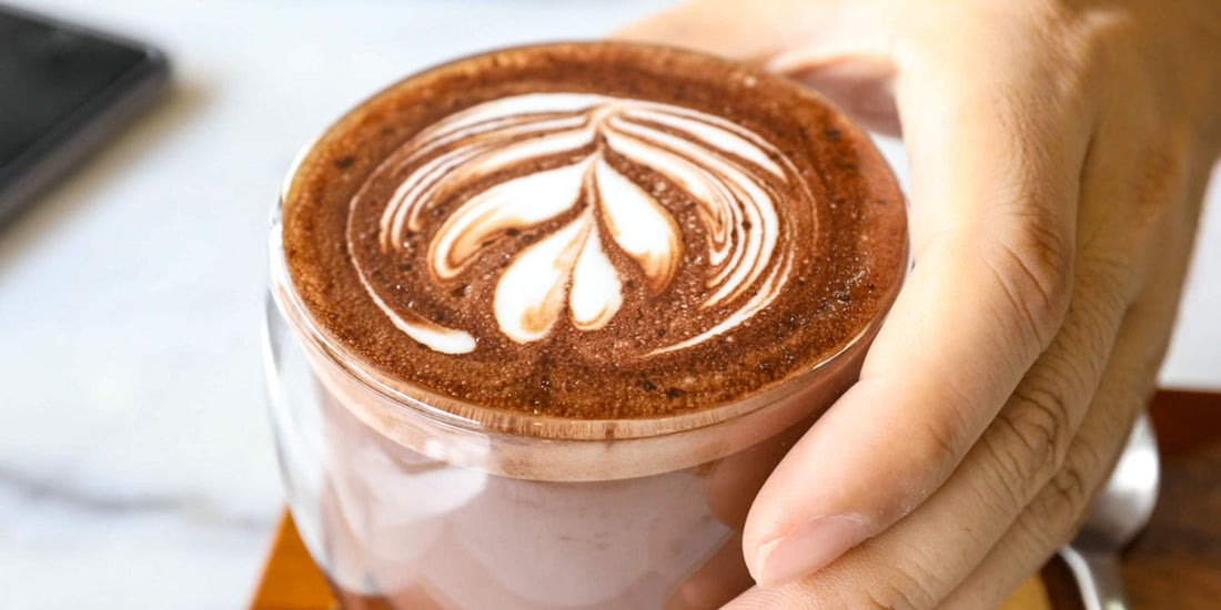 Hand holding a warm cup of gratitude coffee with latte art.